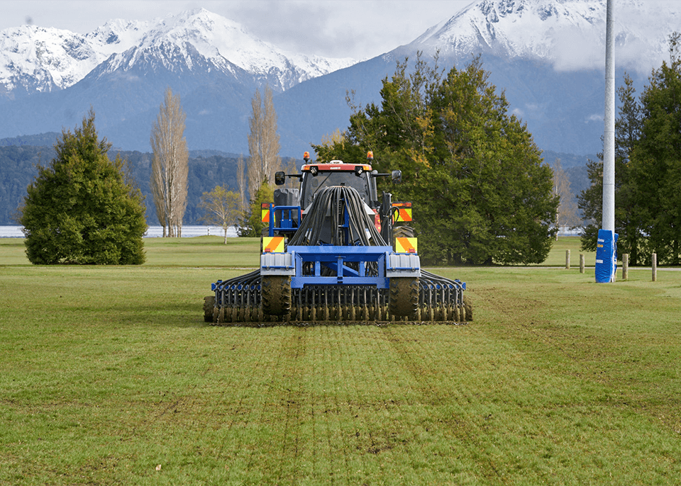 Tractor pulling direct drilling equipment at Te Anau Rugby Club field